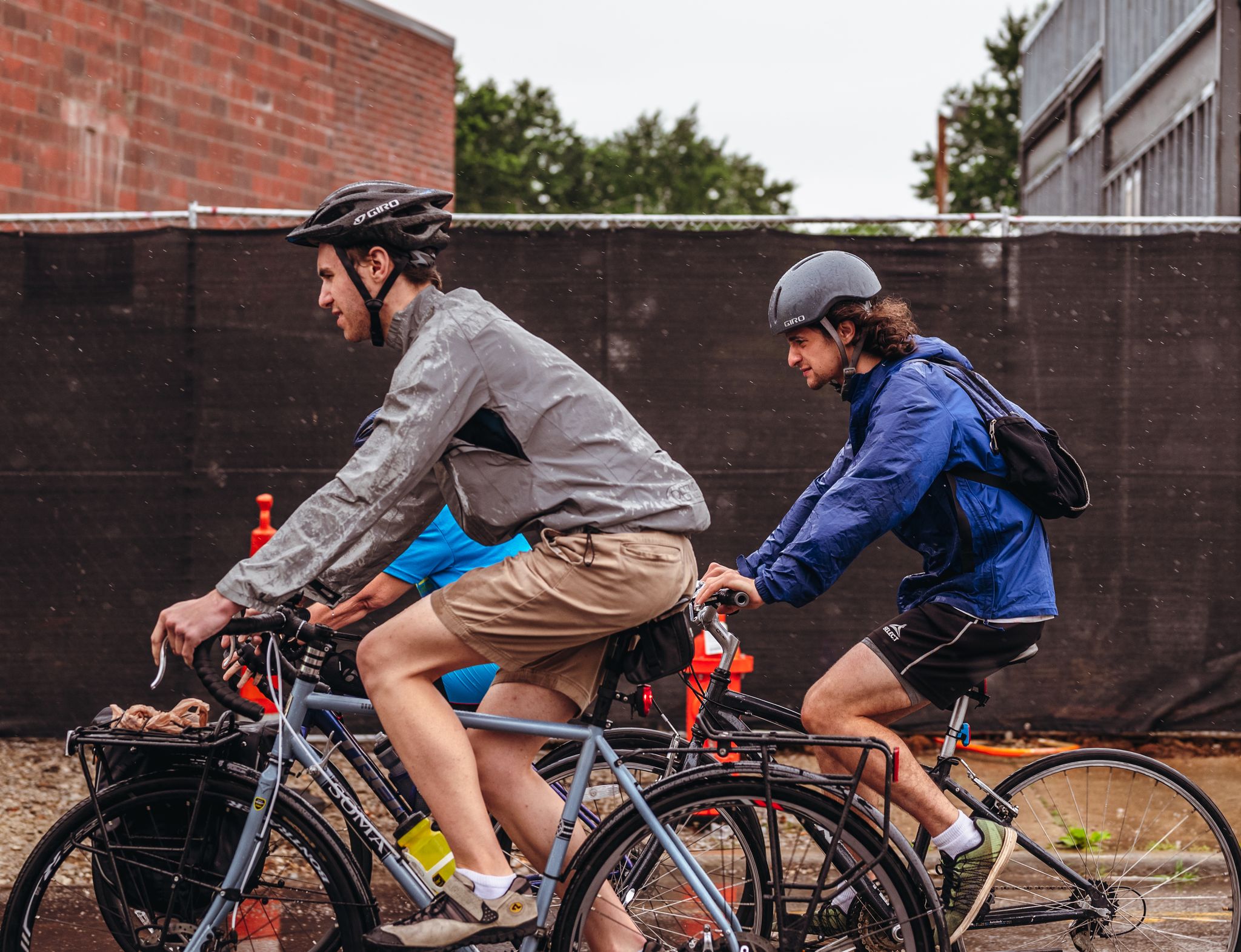 Three men cycling through an urban area during a rainy day, showcasing an active outdoor lifestyle.